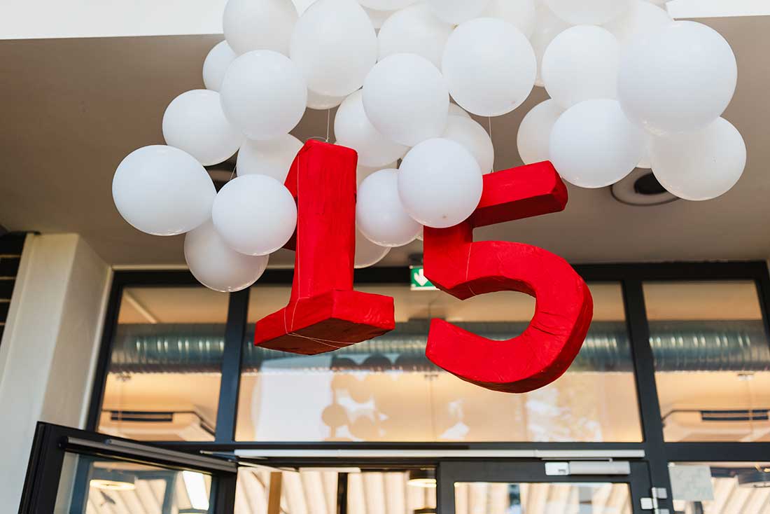 Weiße Luftballons hängen von der Decke mit einer großen roten 15